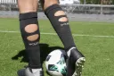 Schwarze Cut Sleeves mit Wadenöffnungen und HOLIES-Schriftzug, getragen am Fußball.